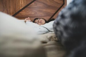 Person sleeping peacefully in bed with natural lighting