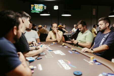Trading cards spread across tournament table with competitive players in background