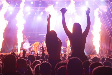 How Roblox Virtual Concerts Are Attracting Major Record Labels Large concert audience with raised hands and stage lighting creating energetic atmosphere