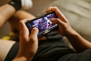 Person playing mobile game on smartphone with colorful game interface visible on screen