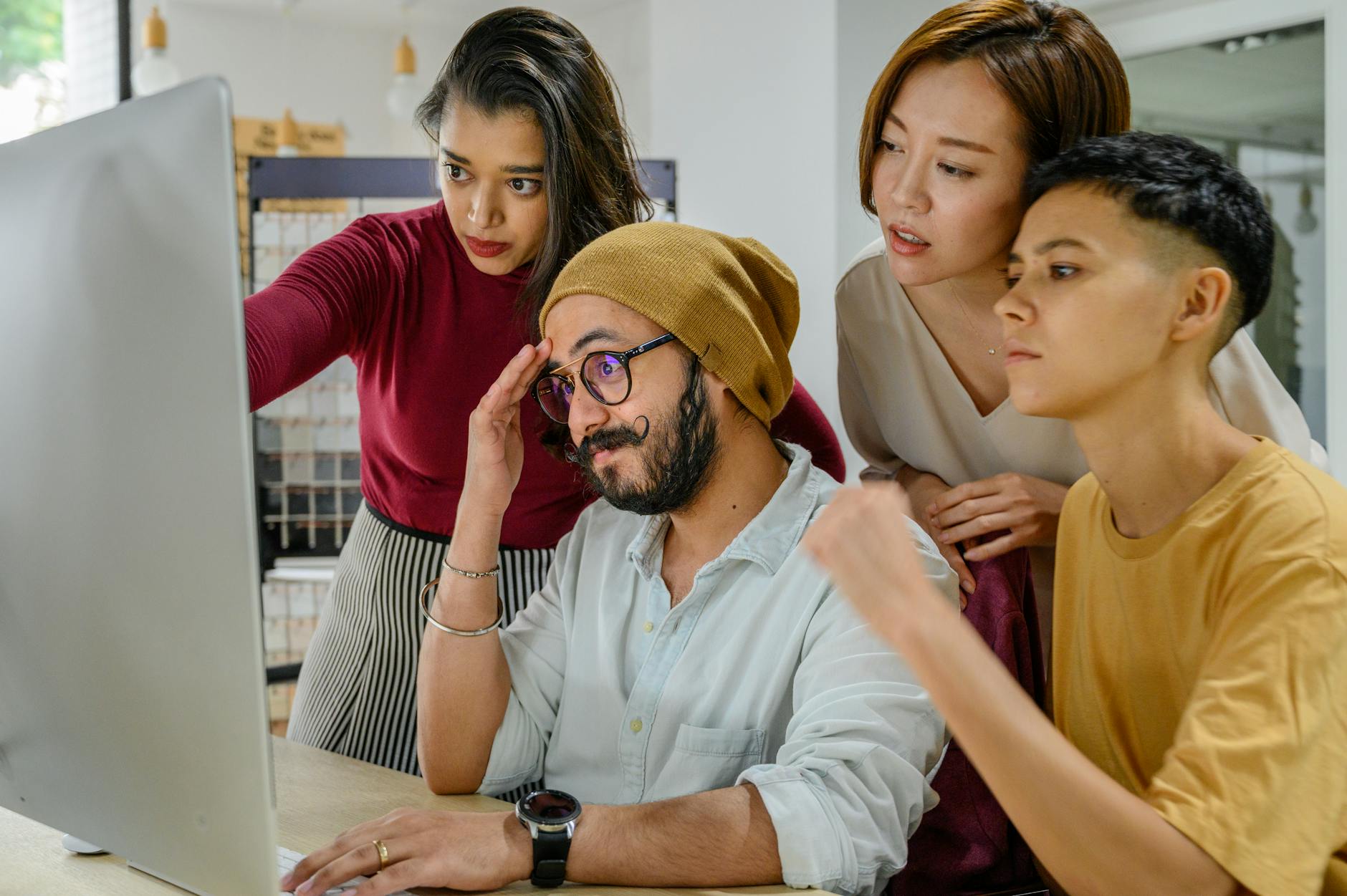 Group of people collaborating around computer screens in gaming environment