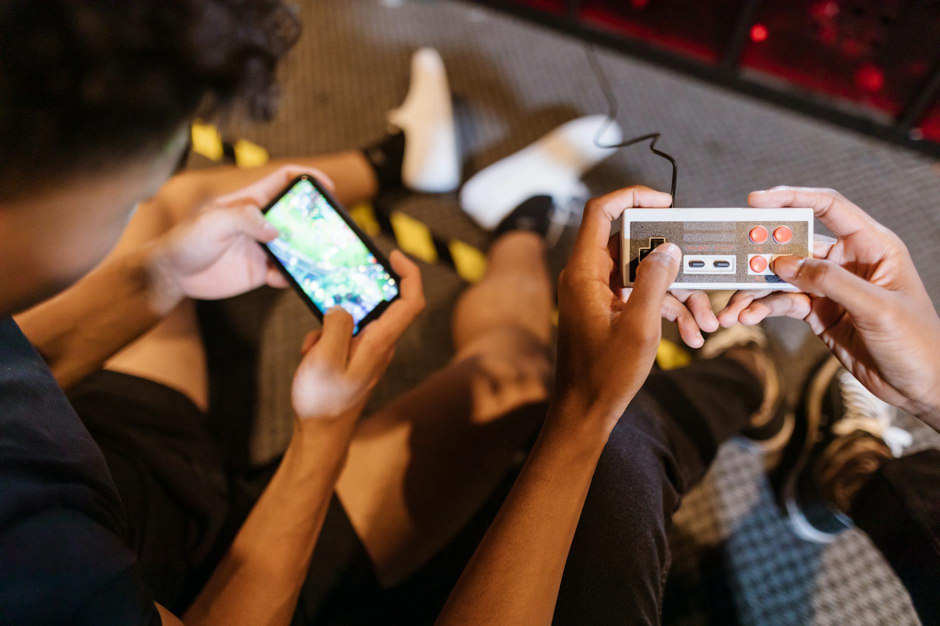 Person holding a gaming controller while playing on a mobile device screen
