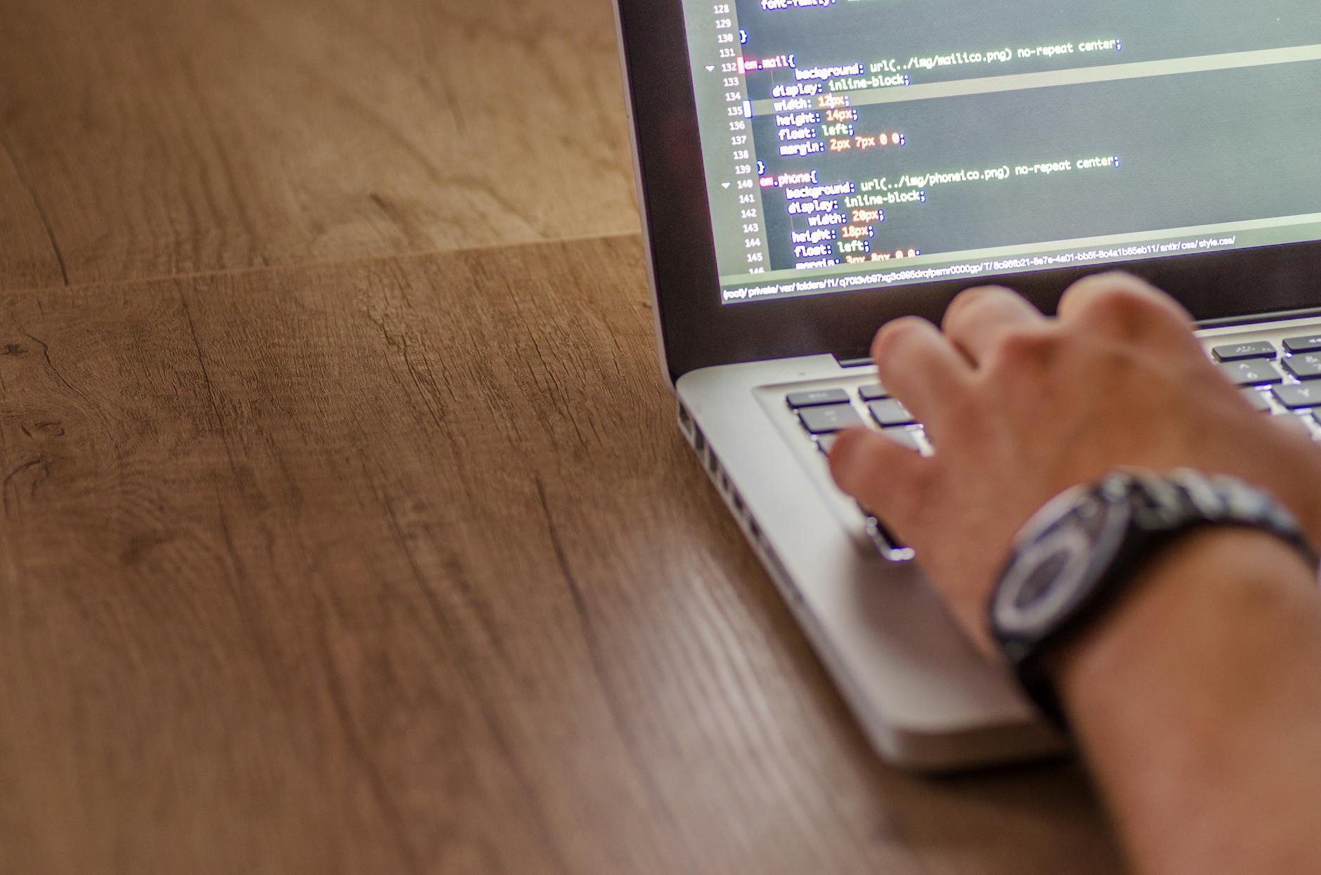 Software developer working on laptop with code editor displaying game development project