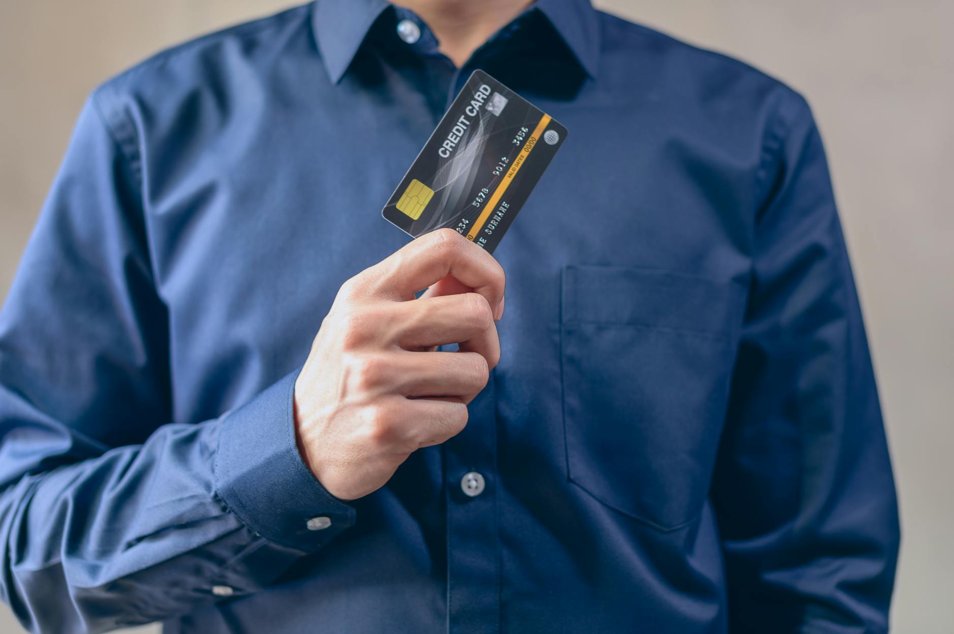 Hand holding credit card near laptop keyboard for online payment transaction