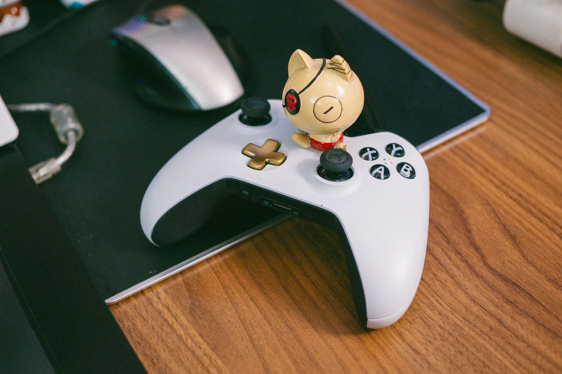 A gaming controller sitting on a desk next to a monitor in a dimly lit room