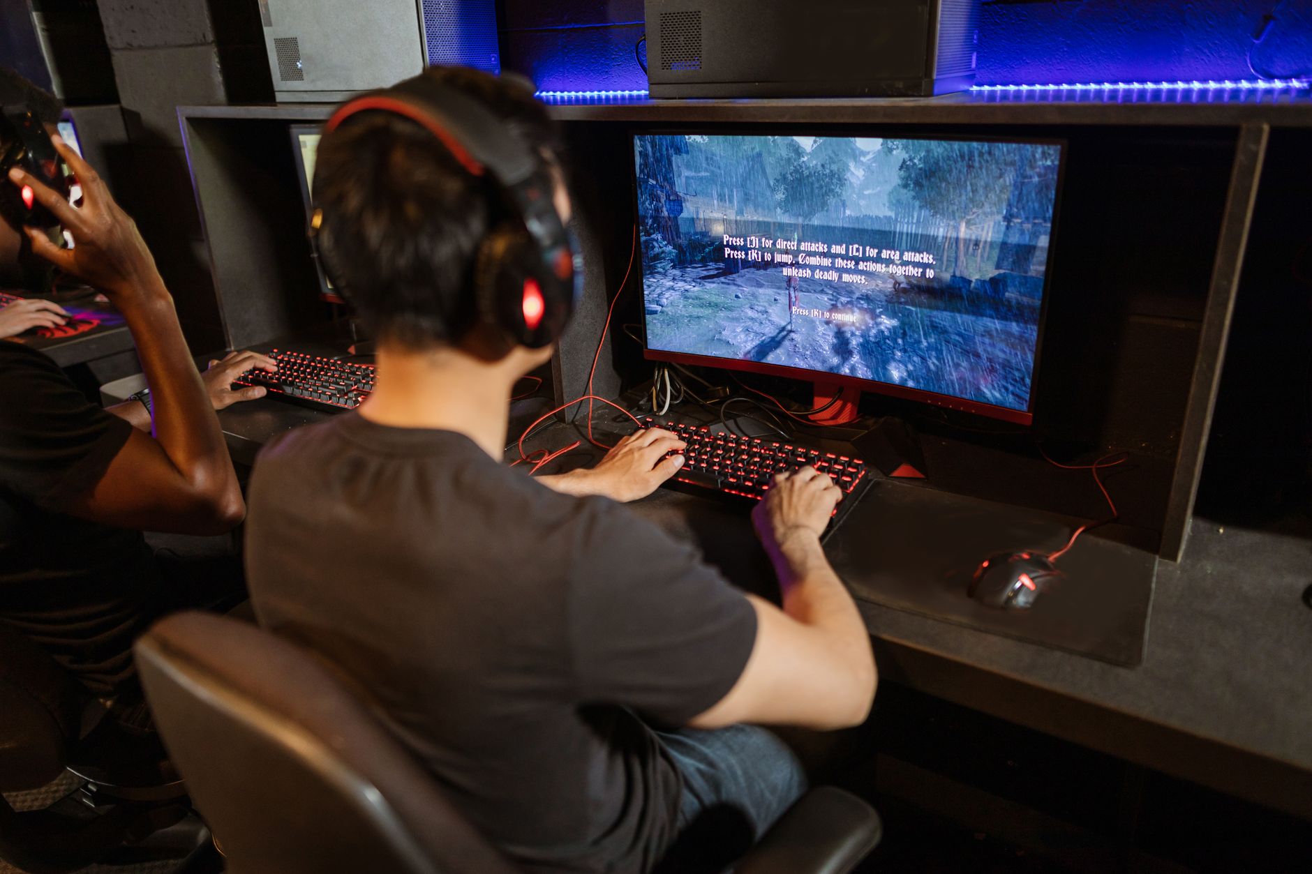 Person sitting in front of a television screen in a dimly lit gaming room
