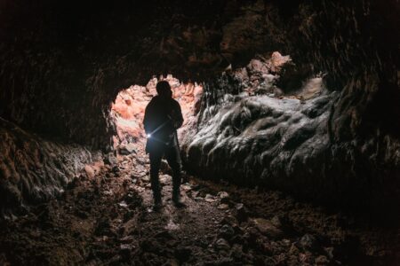 A dark underground cave environment with layered rock formations, representing vertical level design