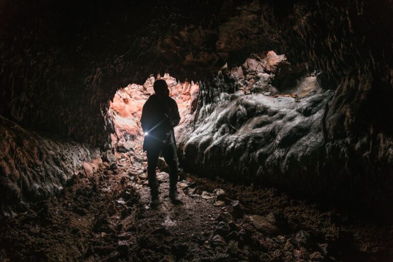 A dark underground cave environment with layered rock formations, representing vertical level design