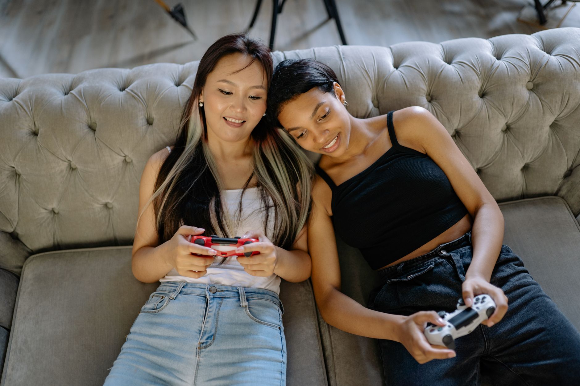 Two people sitting on a couch playing video games together with controllers in hand